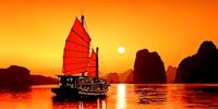 Junk ship sailing on Ha Long Bay at sunset