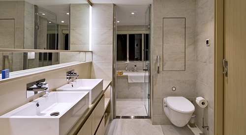 Interior of an Explorer Suite bathroom, with two sinks and marble tile.